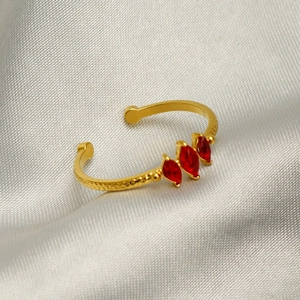 Bague dorée martelée avec trois pierres rouges taille marquise sur fond en soie grise