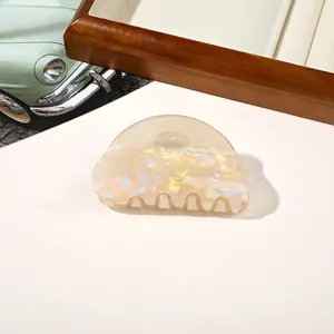 Close-up of a pearlescent semicircular acrylic hair claw clip with aurora shimmer effect