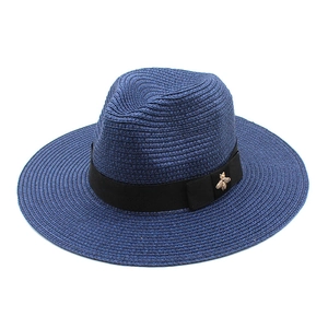 Detail of dark blue fedora sun hat with black ribbon and gold bee metal ornament