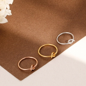 Detailed view of minimalist knot rings in rose gold, gold, and silver stainless steel