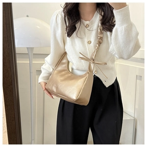 Detail of champagne gold hobo bag featuring pleated shoulder strap and elegant bow design