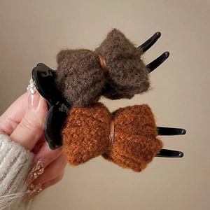 Detailed view of plush knitted bow hair clips in brown and caramel shades for winter