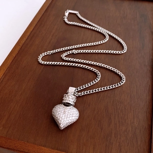 Detailed macro view of heart crown pendant with white zircon on silver curb chain