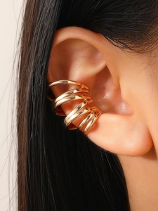 Detailed close-up of a gold multi-layer spiral ear cuff shown on the ear cartilage