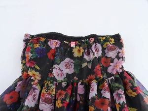 Detailed close-up of elastic ruffled neckline and colorful floral print on organza fabric