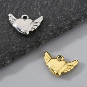 Polished silver and gold heart wing pendants displayed on a textured slate background