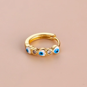 Macro shot of gold hoop earring with evil eye design and cubic zirconia on pink background