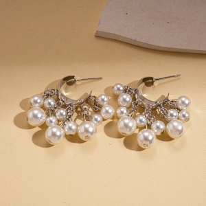 Close-up of vintage geometric C-shaped earrings with faux pearl tassels on silver pins