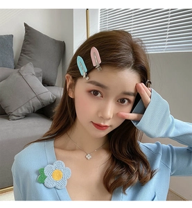 Close-up of a model wearing colorful leaf-shaped no-bend hair clips and a knitted flower brooch