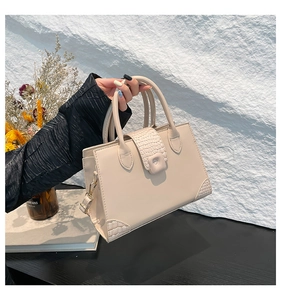 Close-up of cream white handbag with crocodile texture detail and gold hardware
