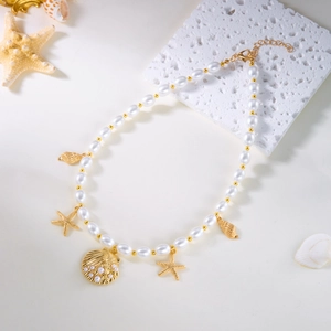 Flat lay of gold shell and starfish pendants on a pearl necklace with marine props