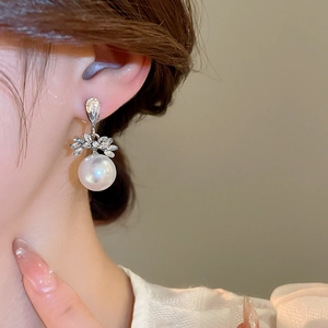 Gros plan d'une femme portant des boucles d'oreilles perles et zircon en forme de feuille