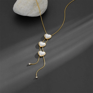 Elegant gold snake chain necklace featuring triple pearl heart pendants and long tassels