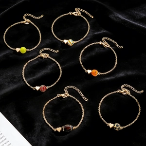 Lot de six bracelets dorés avec breloques de sport sur fond en velours noir