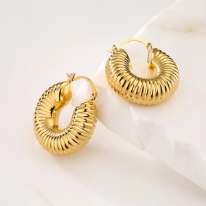 Classic gold-plated croissant hoop earrings with ribbed texture on white marble background