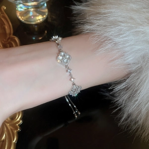 Close-up of a sparkling silver clover bracelet with white zircons on a model's wrist