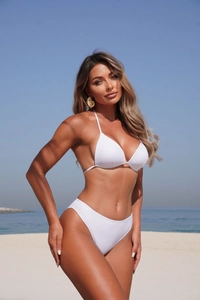 Close-up of white halter bikini and beach skirt set with gold seashell earrings