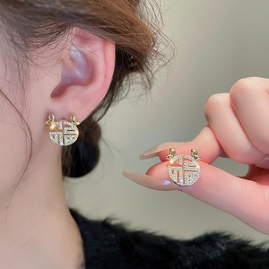 Elegant Chinese style golden Fu character stud earrings with zircon crystals on model