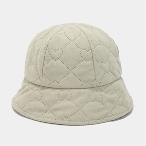 Detailed close-up of heart-shaped quilted pattern and ribbed corduroy texture on cream bucket hat