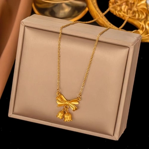 Macro detail of golden bow and lily of the valley flower pendant on textured jewelry box