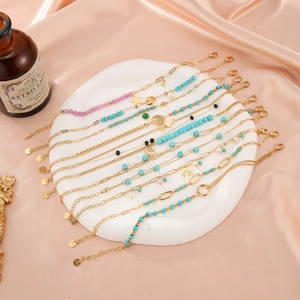 Golden titanium steel bracelets set with turquoise and heart charms on a white stone tray