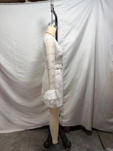 Detail view of white lace dress with elegant bell sleeves and a matching waist belt