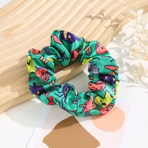 Detail of green silk scrunchie with festive Halloween prints including pumpkins and ghosts
