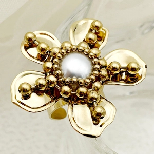 Macro shot of gold floral ring with white pearl center and intricate metal petals