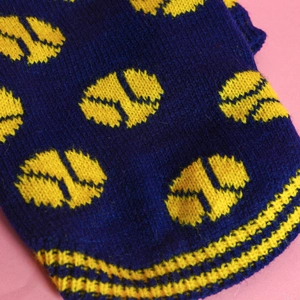 Detailed view of dog sweater with navy blue knit texture and yellow polka dot pattern