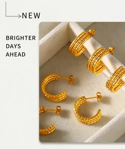 Detailed view of triple-layered C-shaped gold-plated steel earrings with textured finish