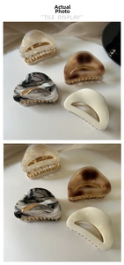Detail view of four acetate hair claws in marble and tortoiseshell patterns on gold base