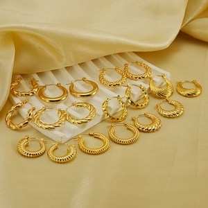 Detailed close-up of various textured 18K gold-plated hoop earrings on silk background