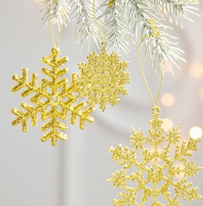 Close-up of golden glitter snowflake ornaments hanging on frosty pine branches with lights