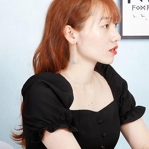 Detail of silver geometric triangle tassel earrings showing the drop length on a model