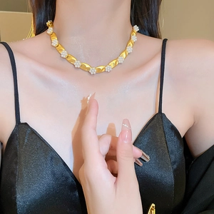 Close-up of a vintage gold chain necklace with delicate pearl flower clusters on a model