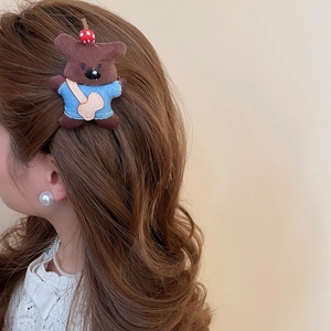 Detail of a brown plush bear hair clip with a blue shirt and guitar bag on hair