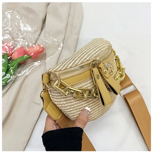 Detail of straw chest bag with yellow leather trim and decorative metal chain detail