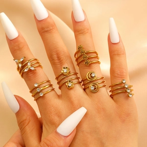Detail of gold zircon rings featuring butterfly and moon shapes on champagne satin silk