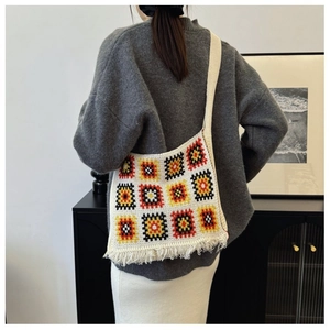 Detail of a handmade granny square knit tote bag featuring colorful patterns and fringe tassels