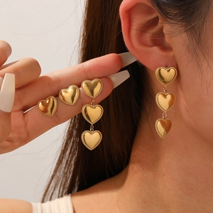 Polished gold heart drop earrings and studs in a layered minimalist fashion design