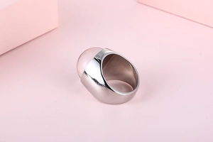 Close-up of wide silver ring with a polished oval pink glass stone on a minimal background