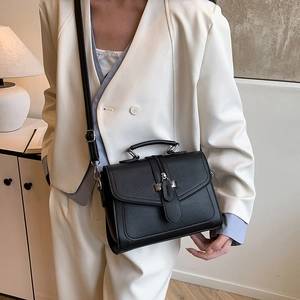 Classic black PU leather crossbody bag with silver hardware on a chic beige blazer