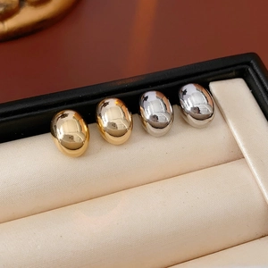 Close-up of gold and silver bean stud earrings displayed in a luxury jewelry gift box