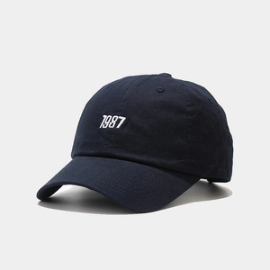 Detailed view of navy blue cotton baseball cap featuring 1987 white 3D embroidery