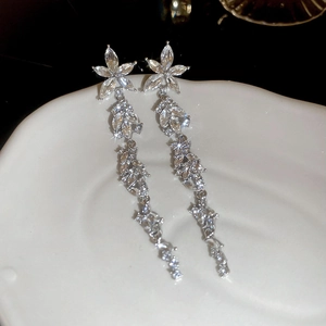 Elegant silver long tassel flower earrings with sparkling rhinestones on a ceramic tray