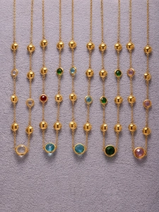 Detail of colorful faceted gemstones on golden station necklaces with gold beads