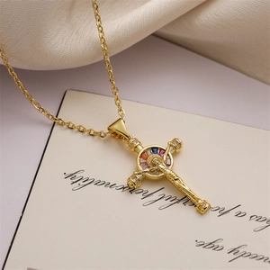 Close-up of gold cross necklace featuring a halo set with colorful gemstones on a card
