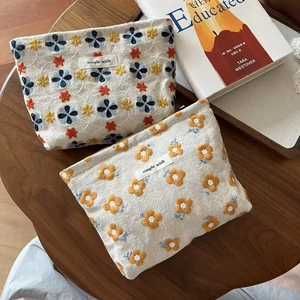 Detail of embroidered cotton linen pouches with floral patterns on a rustic wooden table