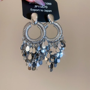 Macro detail of bohemian silver earrings featuring circular weave and teardrop fringe