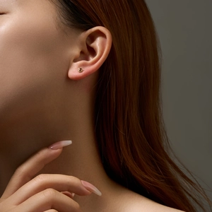 Close-up of minimalist gold S925 silver stud earring with round red gemstone on ear